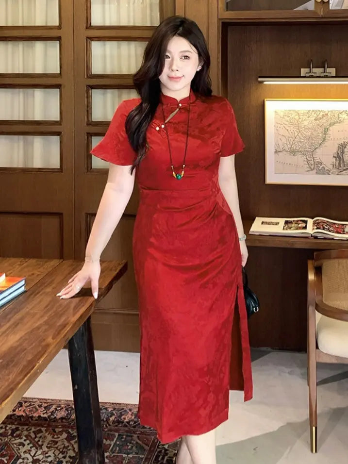 A woman wearing a Plus Size Cinnabar Red Modern midi  Qipao  cheongsam dress with a high slit, standing in a warm-toned indoor room with wooden furniture.