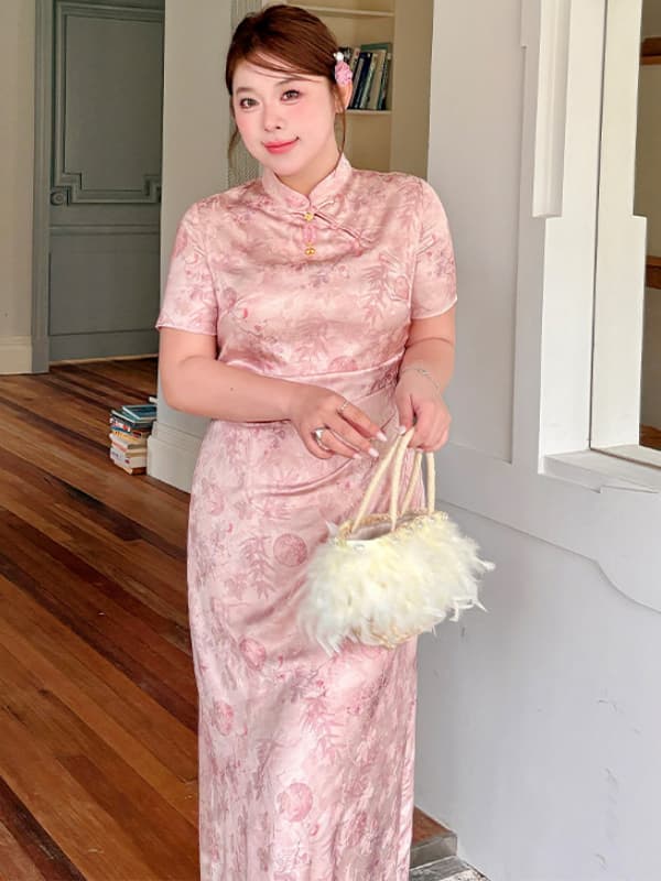 A woman wearing a light pink short-sleeve plus size qipao cheongsam dress with a subtle tonal floral pattern, holding a white feathered handbag in an indoor setting with wooden floors and white walls.