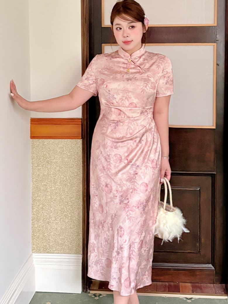 A woman wearing a pink floral-patterned short-sleeve plus size qipao cheongsam dress, holding a white fluffy handbag, standing in front of a dark wooden door.