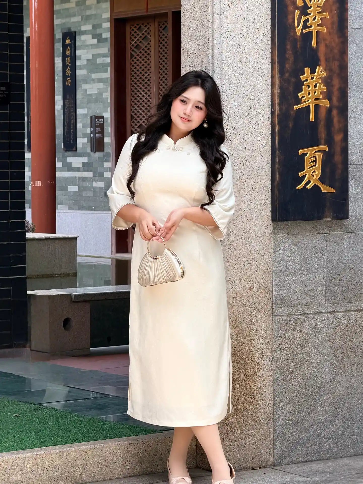 Woman in aPlus Size Ivory White Floral Long Sleeve Jacquard Qipao dress standing in front of a building with Chinese characters.