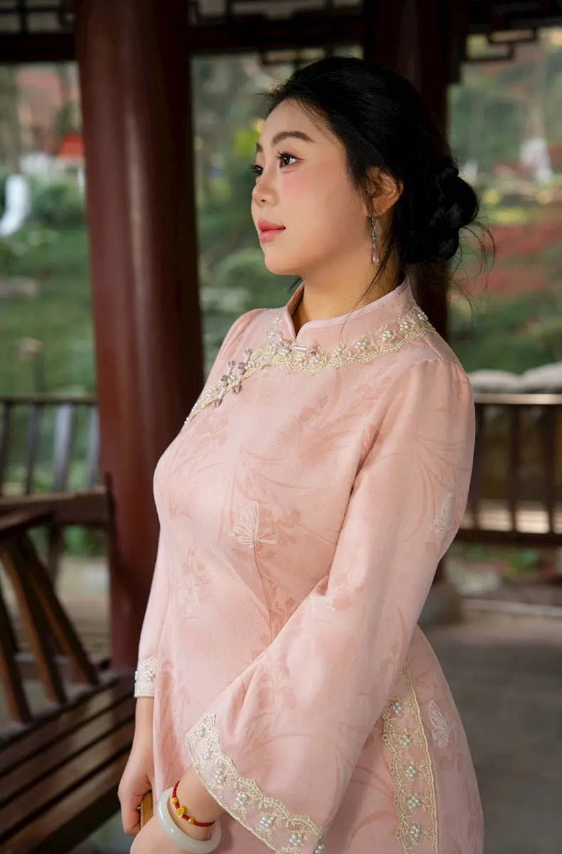 Woman wearing a pink traditional chinese qipao cheongsam outfit with intricate details, standing outdoor