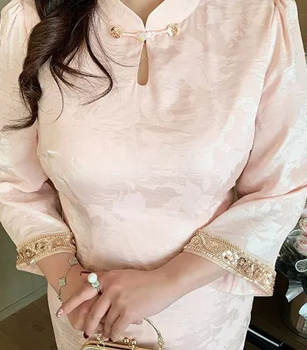 Plus Size Modern Pink Long Sleeve Jacquard Qipao  traditional outfit with gold embroidery on a blurred background