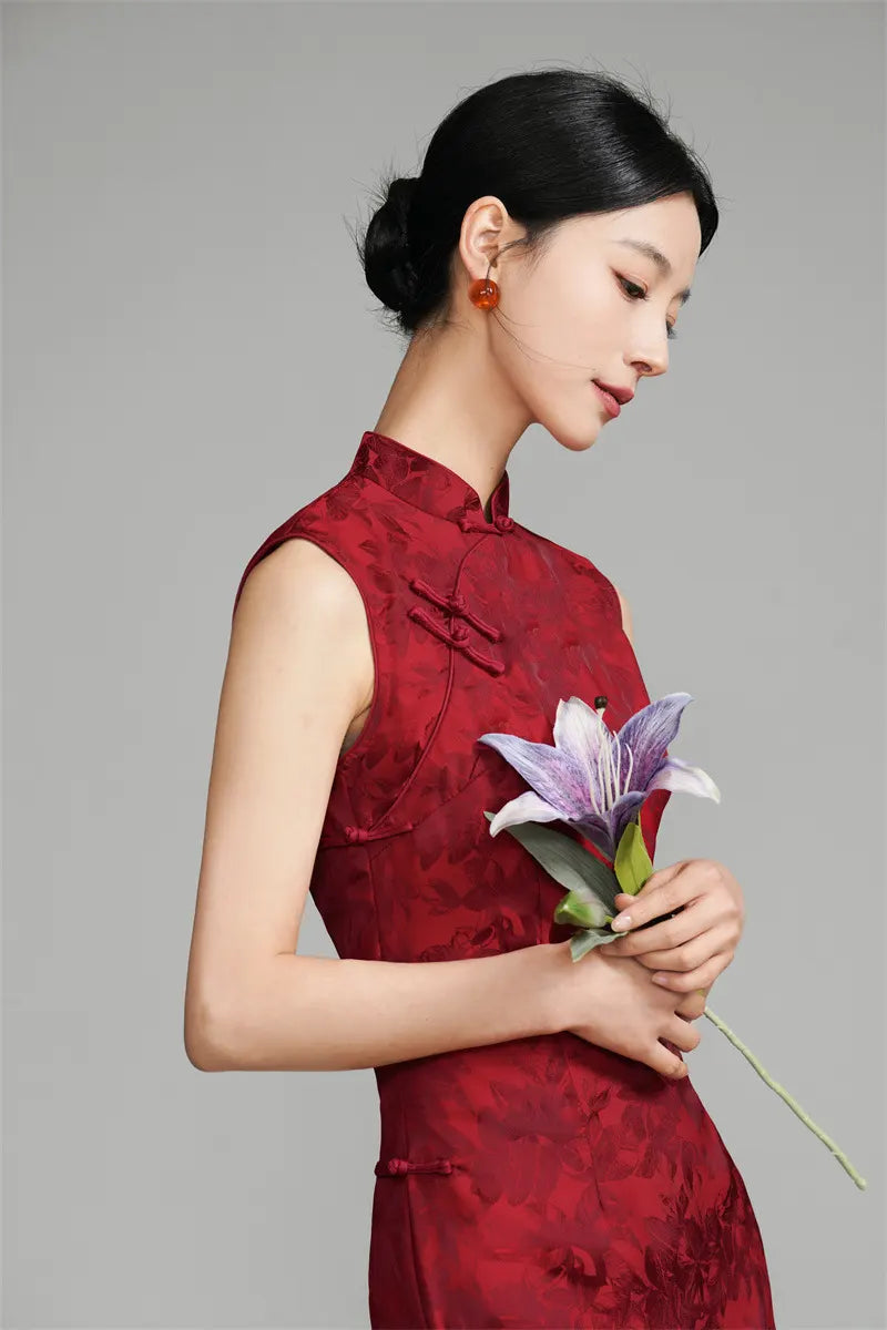 Woman in a Red Sleeveless Floral Jacquard wedding Cheongsam Qipao Dress holding a flower against a gray background