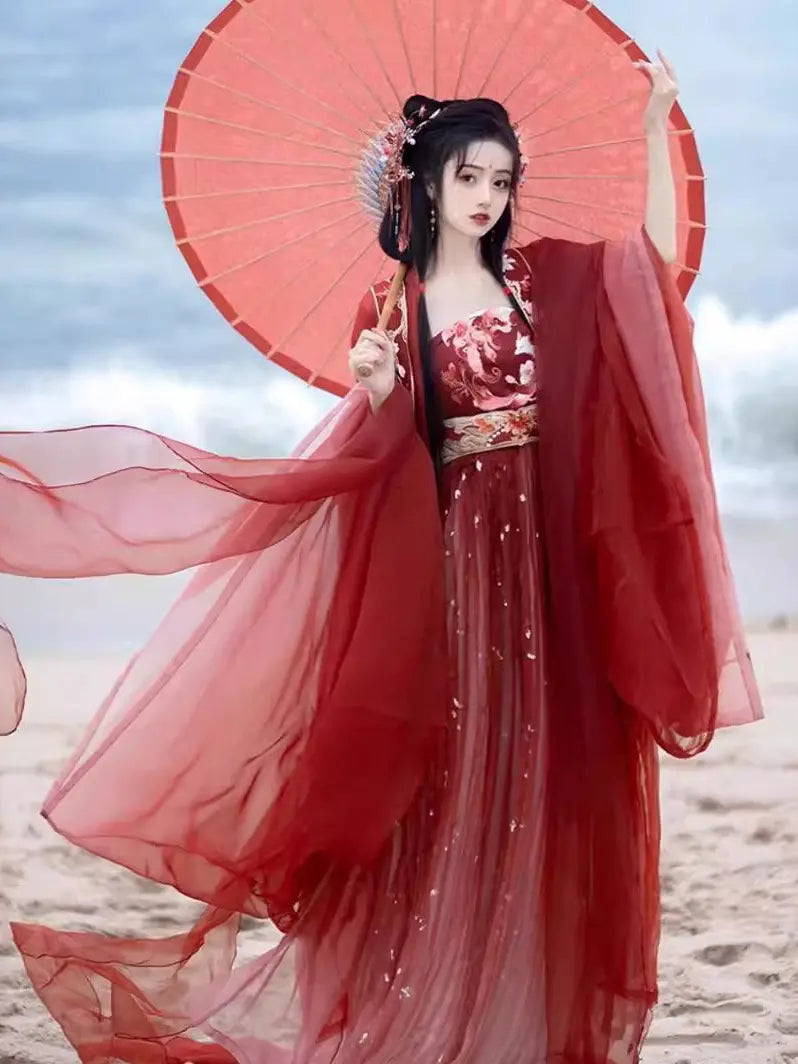 Woman in traditional Red Ancient Chinese Imperial Tang Dynasty Hanfu Set holding a red parasol on a beach