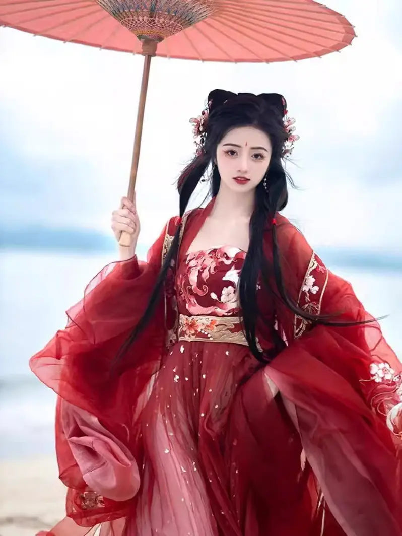 Person in traditional Red Ancient Chinese Imperial Tang Dynasty Hanfu Set holding a red umbrella against a blurred natural background