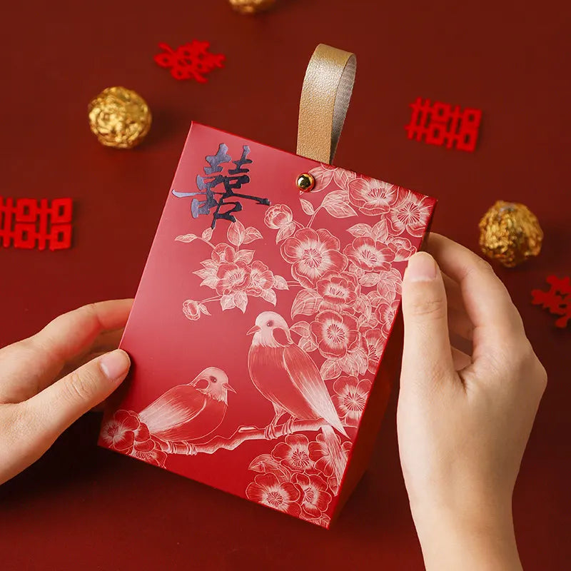 Red & Black Double Happiness Wedding Favor Box – Blossom & Bird design held by hands on a red background