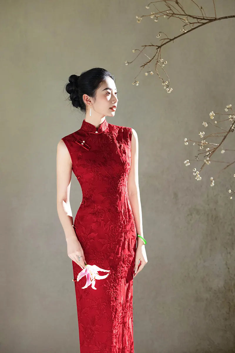 Woman in a red  Floral Embroidery Sleeveless Qipao  dress standing against a neutral background with a branch with small flowers.