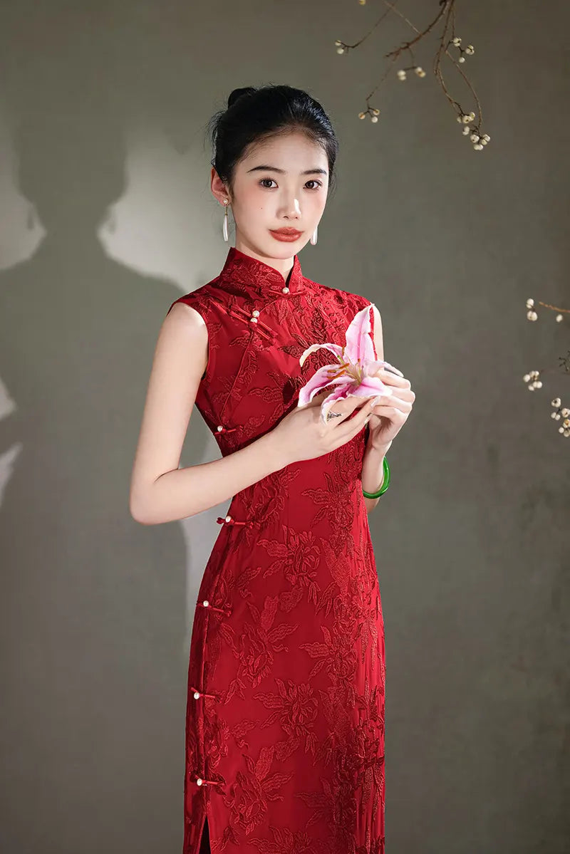 Woman in a red traditional  Floral Embroidery Sleeveless Qipao dress holding a pink flower against a neutral background
