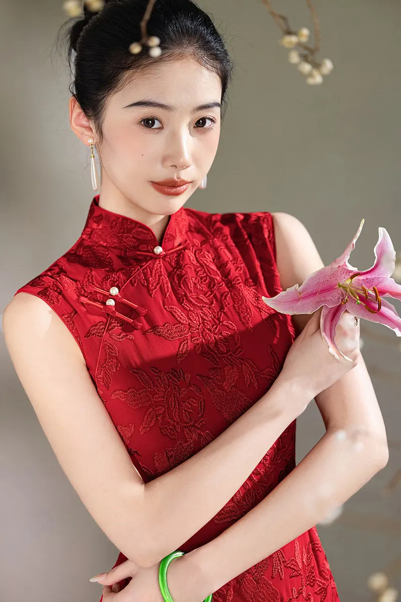 Woman in a traditionalRed Floral Embroidery Sleeveless Qipao  outfit holding a pink flower against a neutral background