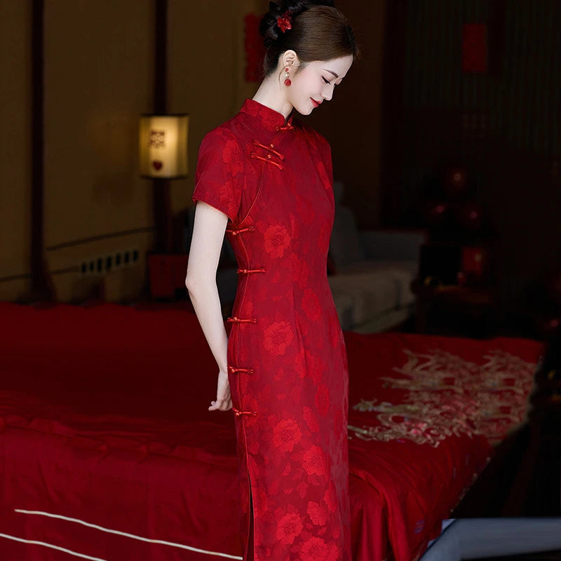 Woman in a red traditional  Floral Qipao Cheongsam Dress standing in a dimly lit room.