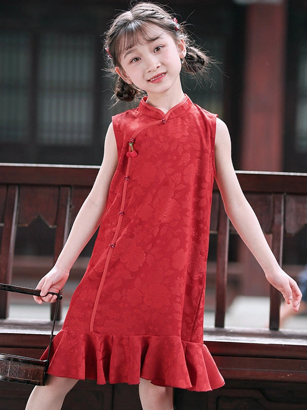 A young girl with braided hair wearing a Red Floral Summer Sleeveless Qipao Dress for Girls  dress with a ruffled hem, standing in front of a dark wooden railing.