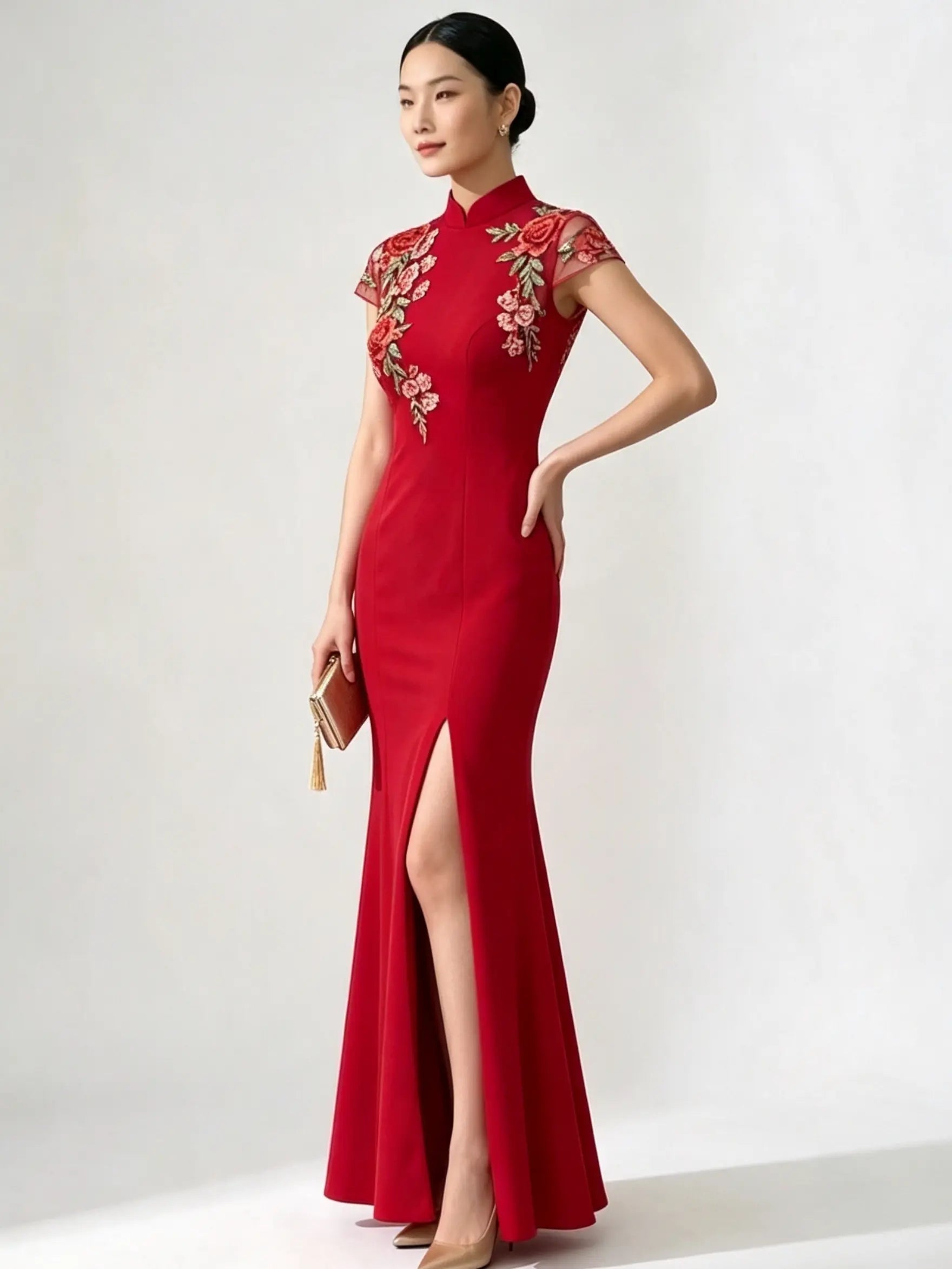 A woman modeling a red cheongsam-style formal gown with floral embroidery on the bodice and sleeves, standing against a plain light gray studio background.