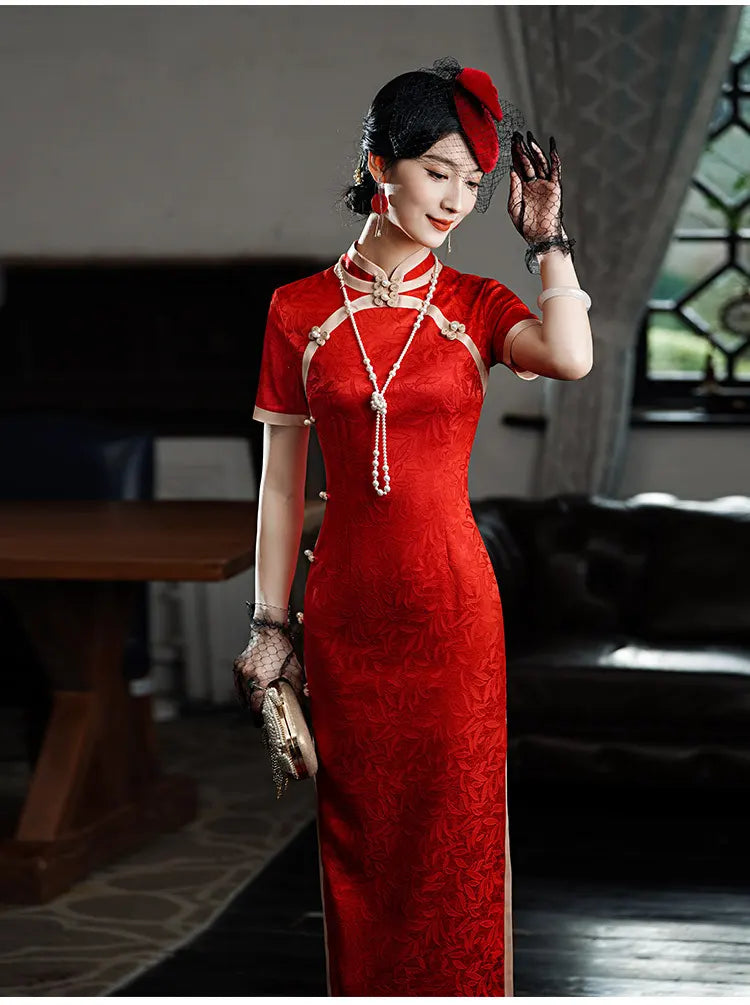 Woman in aRed & Gold Foral Jacquard Qipao - Chinese Wedding Tea Ceremony Dress  with intricate patterns, standing indoors.