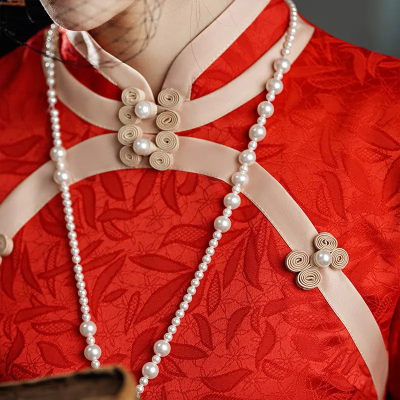 Red garment with Gold trim and pearl decorations on a plain background