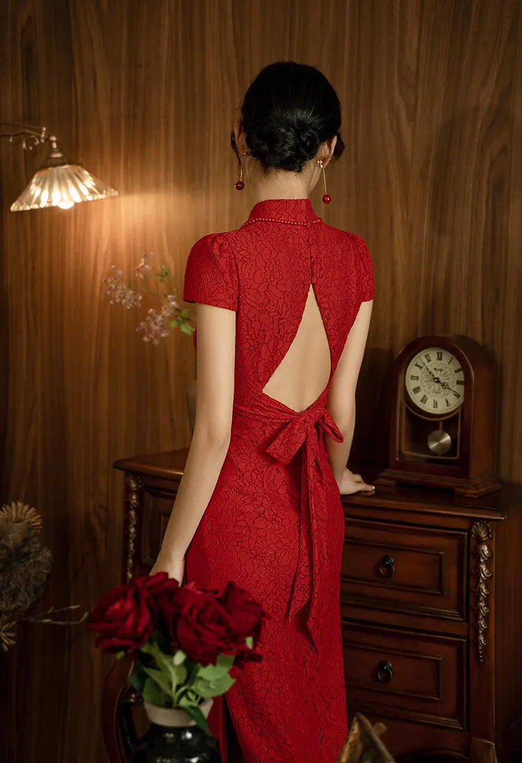 Woman in a Red Lace Open Back qipao Wedding Dress with an open back standing in a room with wooden furniture and a clock.