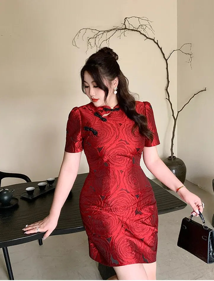 Woman in aRed Plus Size Modern Rose Jacquard Qipao Cheongsam dress standing in a room with a table and decorative plant.