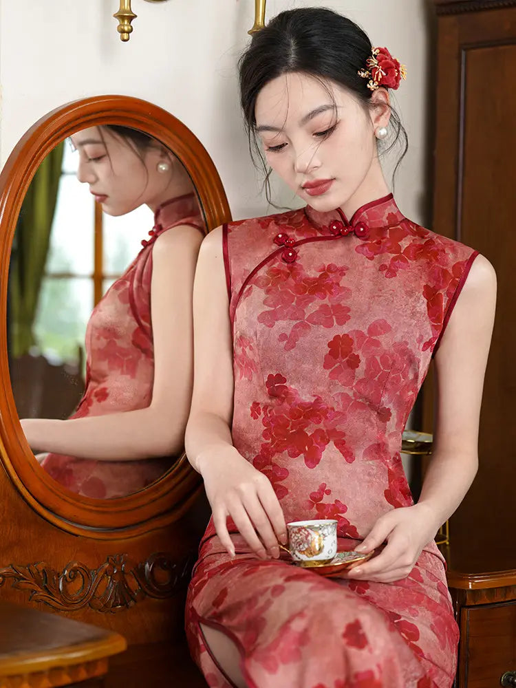 Woman in a Red Sleeveless Floral Qipao Dress – Modern Chinese Cheongsam sitting next to a mirror, holding a teacup.