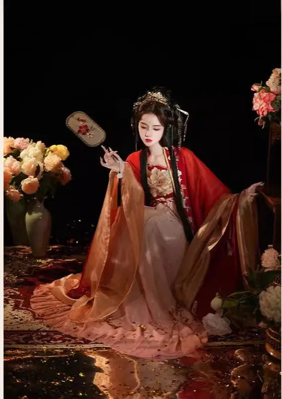 Person in Red and Gold Tang Dynasty Traditional Chiness Hanfu clothing with flowers and a fan in a dark setting