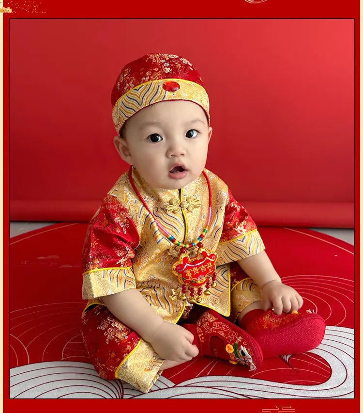 Baby in traditional Chinese Red and Golden Baby Tang Jacket Set  outfit sitting on a red surface with a red background