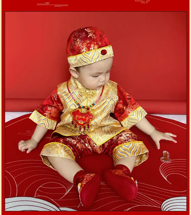 Child in traditional Chinese red and gold outfit sitting on a red background
