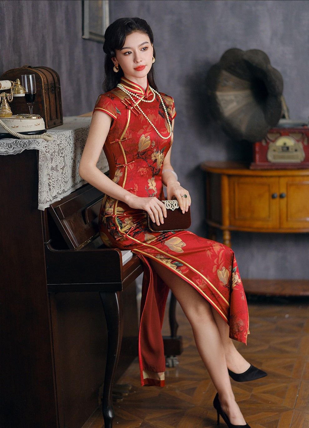 a chinese girl in red long floral silk qipao sitting 