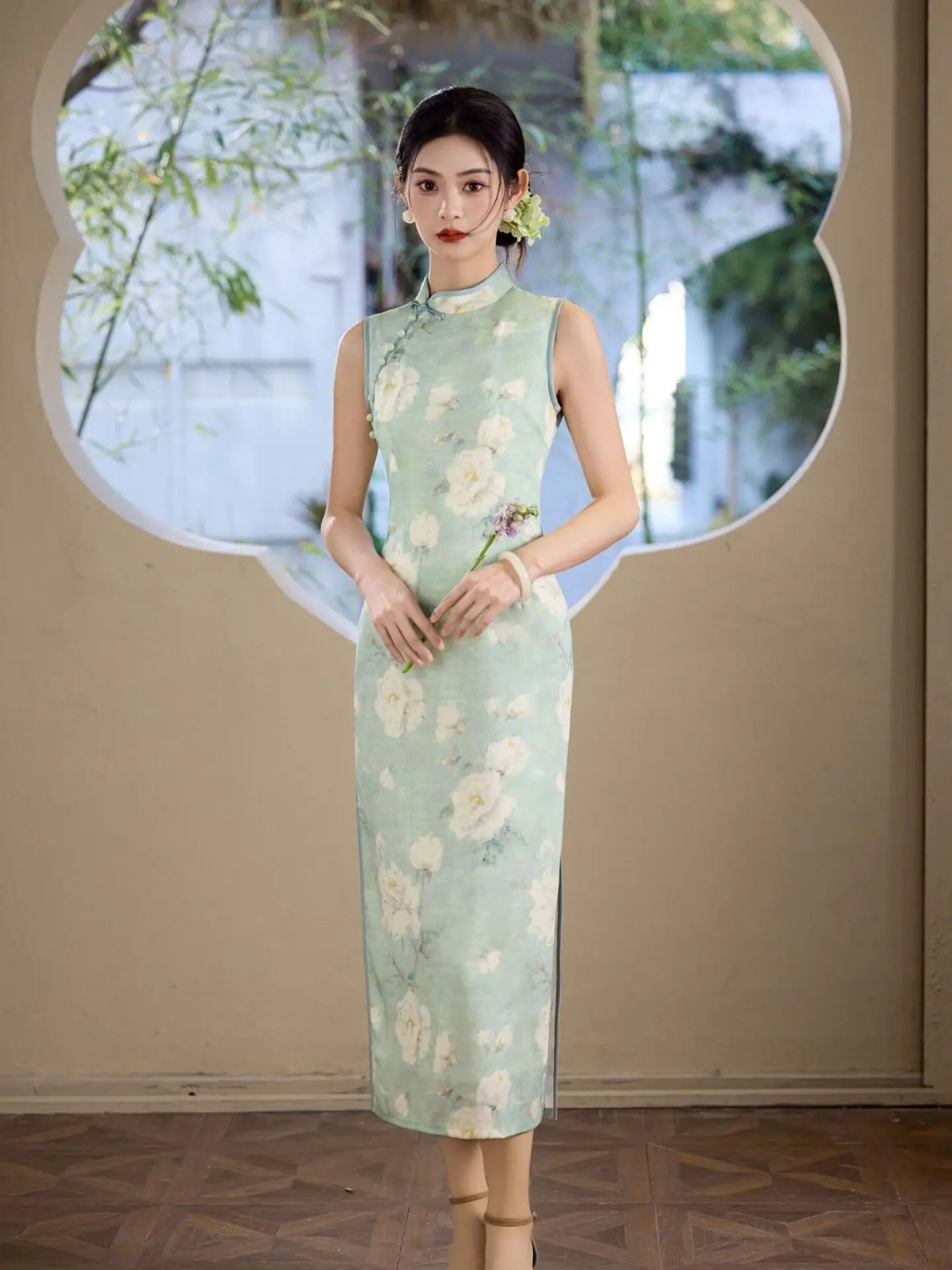Woman wearing a Sage Green Floral Neo-Chinese Sleeveless Qipao Cheongsam  Dress  standing in front of a decorative mirror with a blurred background