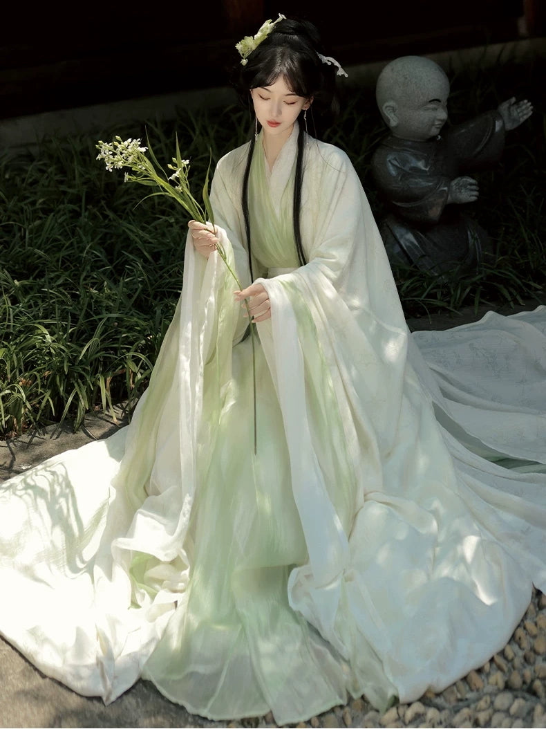 Person in Sage Green Traditional Wei-Jin Style Double-Layer Hanfu Dress Set holding flowers with a statue in the background