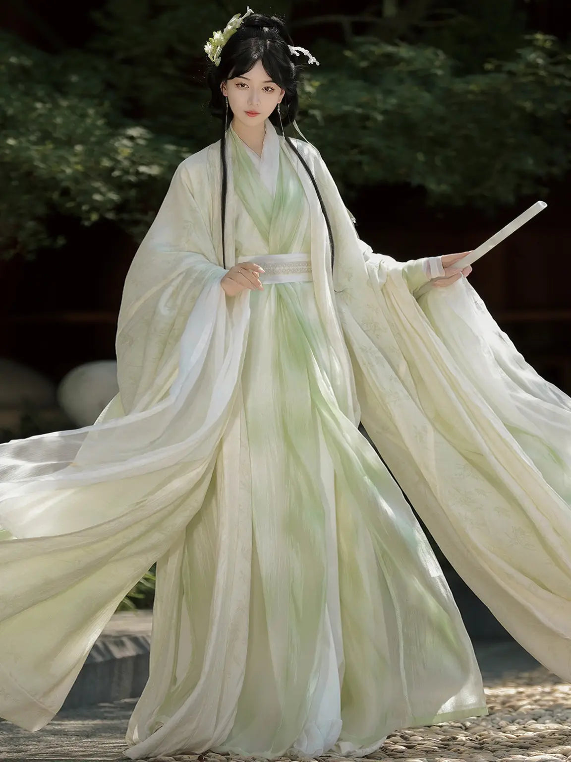 Person in Sage Green Traditional Wei-Jin Style Double-Layer Hanfu Dress Setwith flowing sleeves, standing outdoors.