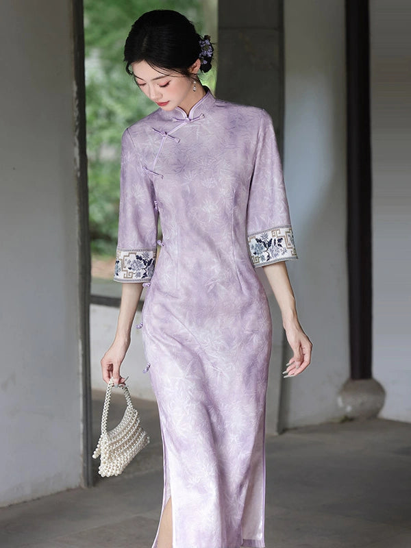 A woman wearing a light purple Soft Lavender Jacquard  3/4 Sleeve Qipao cheongsam dress with white and black patterned cuffs, holding a small white beaded handbag in a traditional architectural setting.