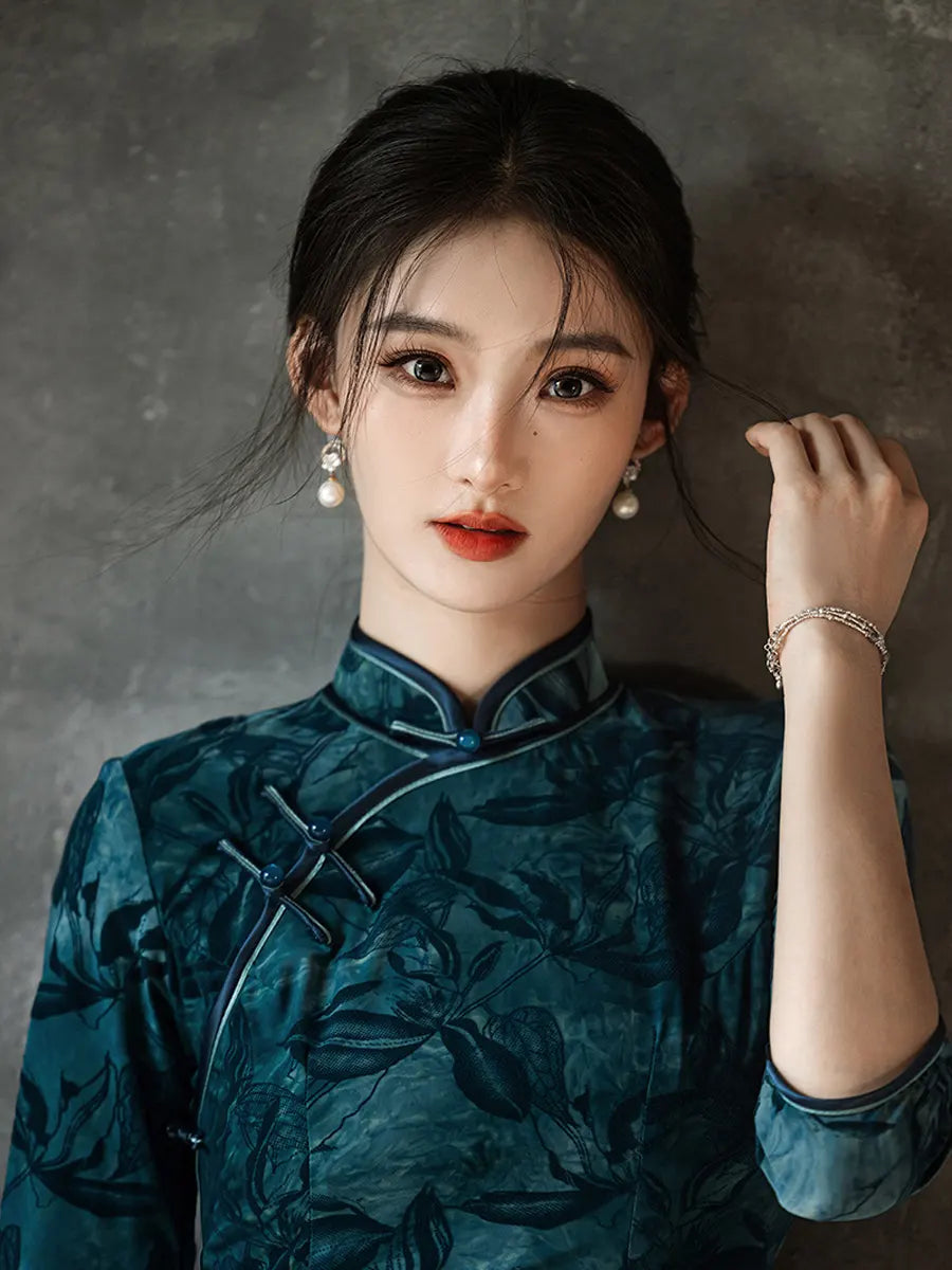 Woman wearing a traditional Teal Foral Velvet Half Sleeves Qipao Cheongsam Dress  against a gray background