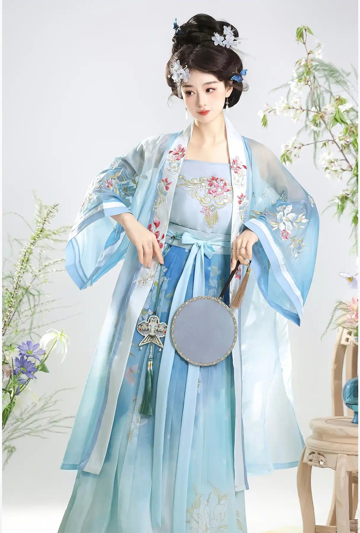 Woman in light blue and white Traditional Chinese Dress – Elegant Song Dynasty Hanfu Set with floral patterns, holding a round fan.