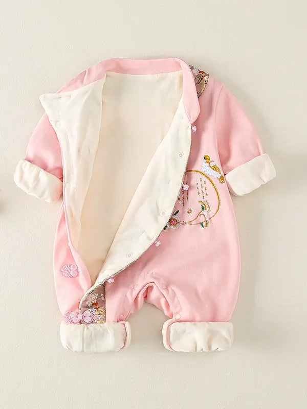 A pink Traditional Chinese Embroidered Baby Girl Qipao Romper  with a cream-colored lining and cuffs, featuring embroidered floral and bird details on the front, displayed against a light beige background.