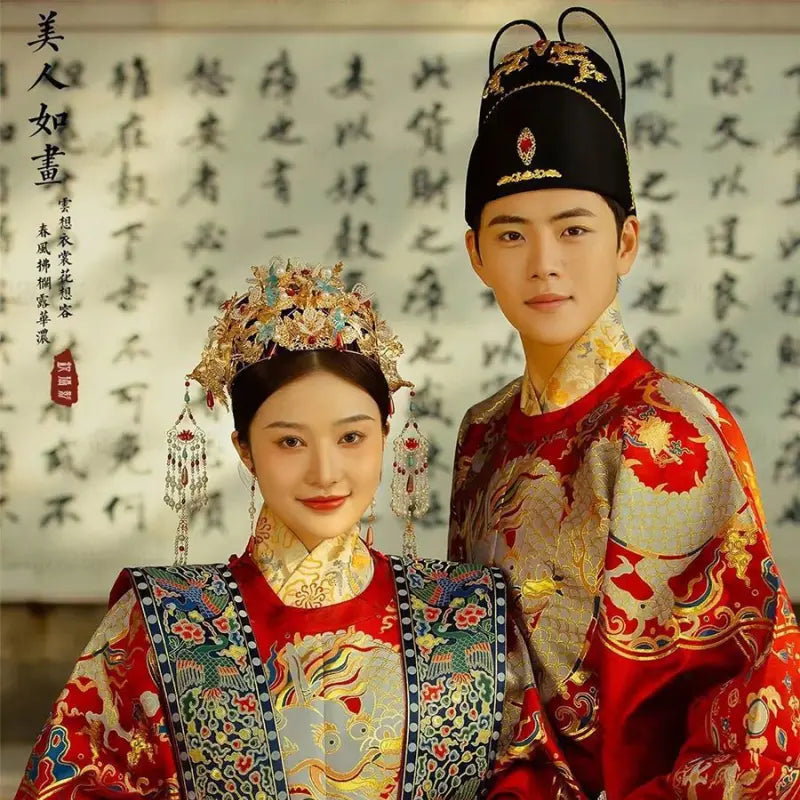 Two individuals in traditional Chinese attire with intricate headpieces against a calligraphy background.