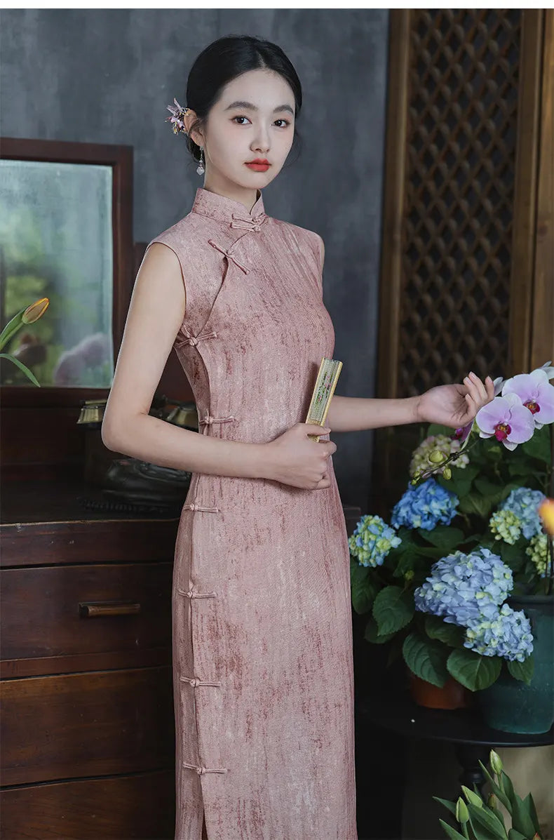 Woman in a Traditional Chinese  Pastel Pink Sleeveless Qipao Cheongsam Dress holding a fan and a flower arrangement indoors.