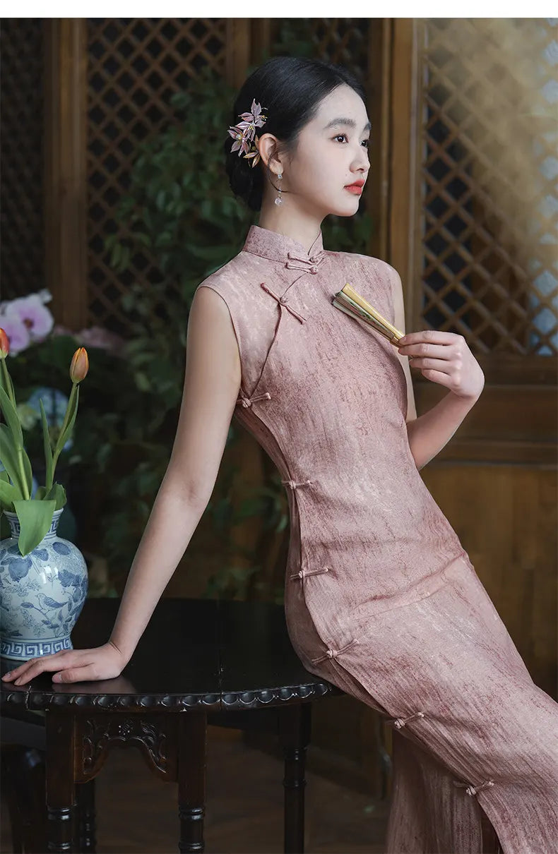 Woman in a Traditional Chinese  Pastel Pink Sleeveless Qipao Dress sitting on a chair with a vase and flowers in the background