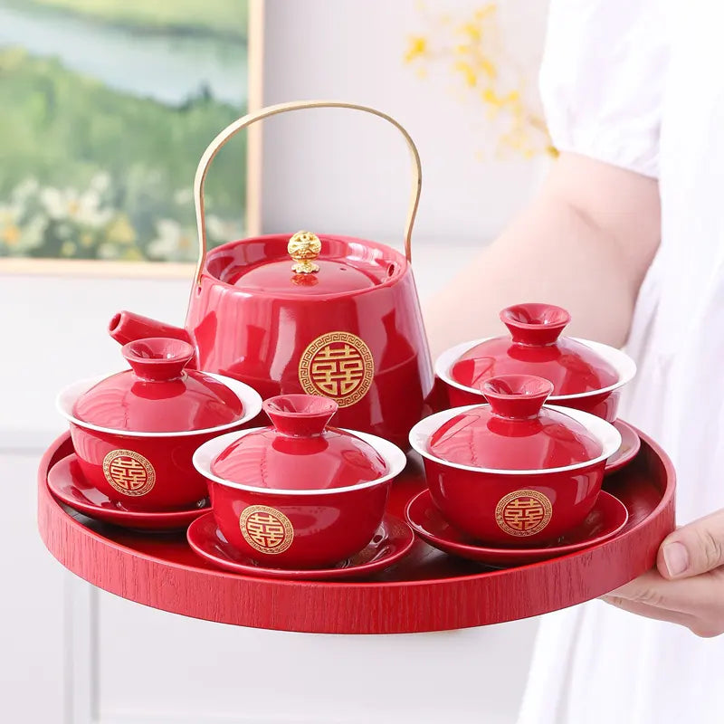 Traditional Chinese Red  Double Happiness Wedding Tea Set  with gold accents on a tray, held by a person.