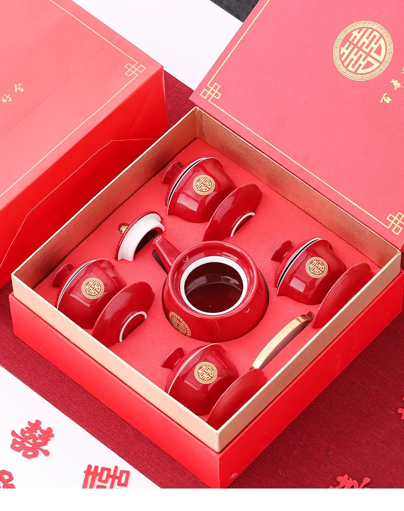 Red ceramic tea set with lid and four cups in a matching box, featuring Chinese characters and patterns.