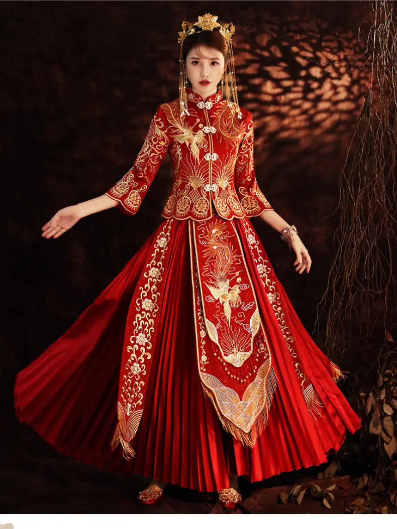 A woman wearing a traditional Chinese red and gold embroidered wedding Qun kwa dress with a pleated skirt, standing against a dark, atmospheric background with warm light