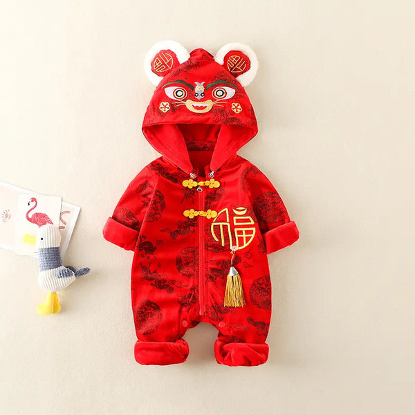 A baby's red Chinese New Year hooded romper with a lion dance costume design, featuring gold Chinese characters and decorative details, displayed on a neutral beige background next to a small plush toy.