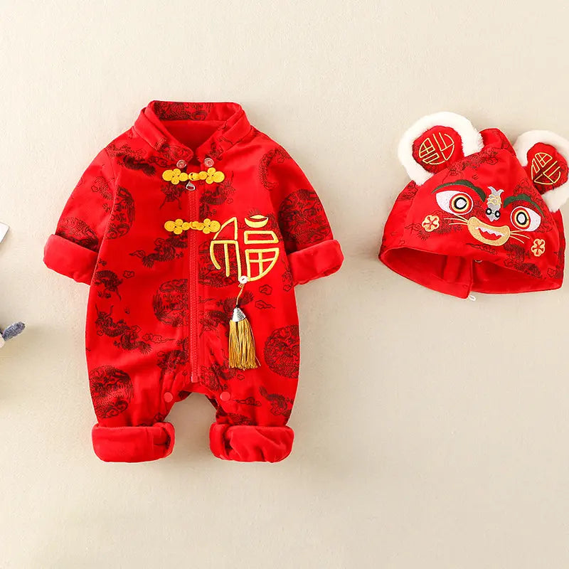 A baby's red Chinese New Year outfit set featuring a long-sleeve romper and a matching hat. The romper has gold Chinese characters and decorative tassels, while the hat features a cute lion face and ears with '福' symbols inside.