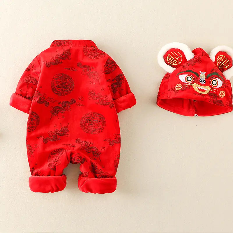 A baby's red traditional Chinese New Year outfit set, featuring a long-sleeve footless romper with a dragon pattern and a matching lion dance hat with white ears and embroidered details, displayed on a light beige background.