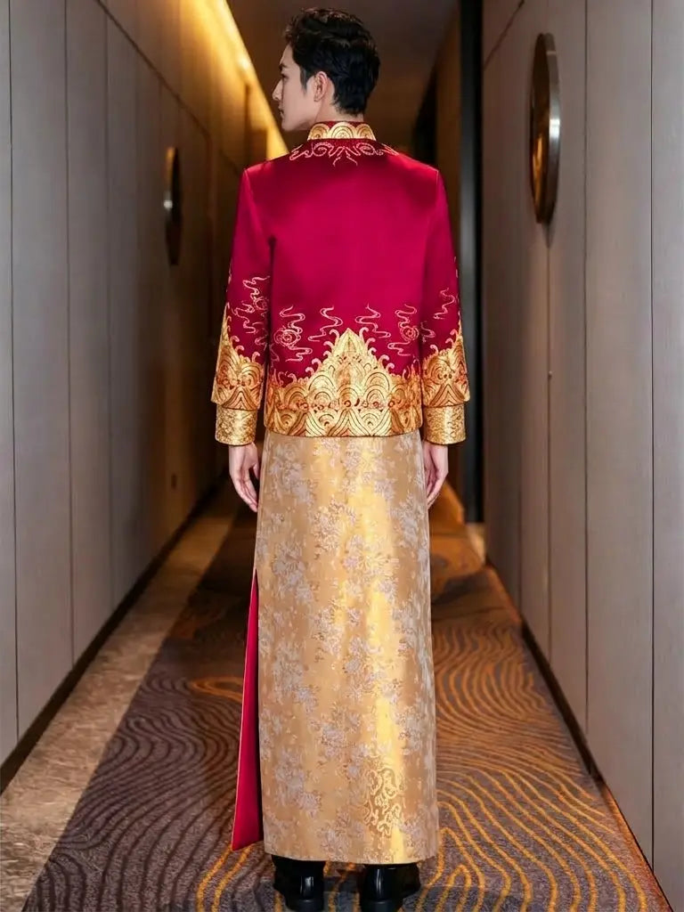 A man viewed from behind wearing a traditional Chinese wedding robe (honghong) in a hotel corridor. The robe features a vibrant red upper back and shoulders with intricate gold embroidery, and a flowing gold patterned skirt.