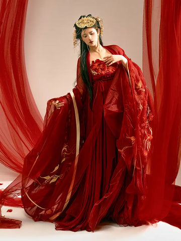 Person in a Traditonal Chinese Red Embroidered Tang Dynasty Hanfu Set gown with floral details against a red curtain backdrop
