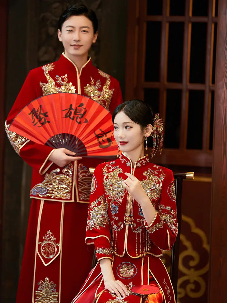groom and bride in Traditonal Chinese Wedding Phoenix & Dragon Qun Kwa Couple Suite  red and gold wedding attire holding a fan with Chinese characters.