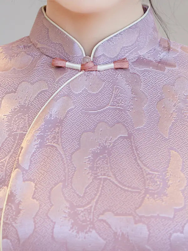 Close-up of a person wearing a lavender satin cheongsam-style top with tonal floral jacquard pattern and pink-and-white frog closures.