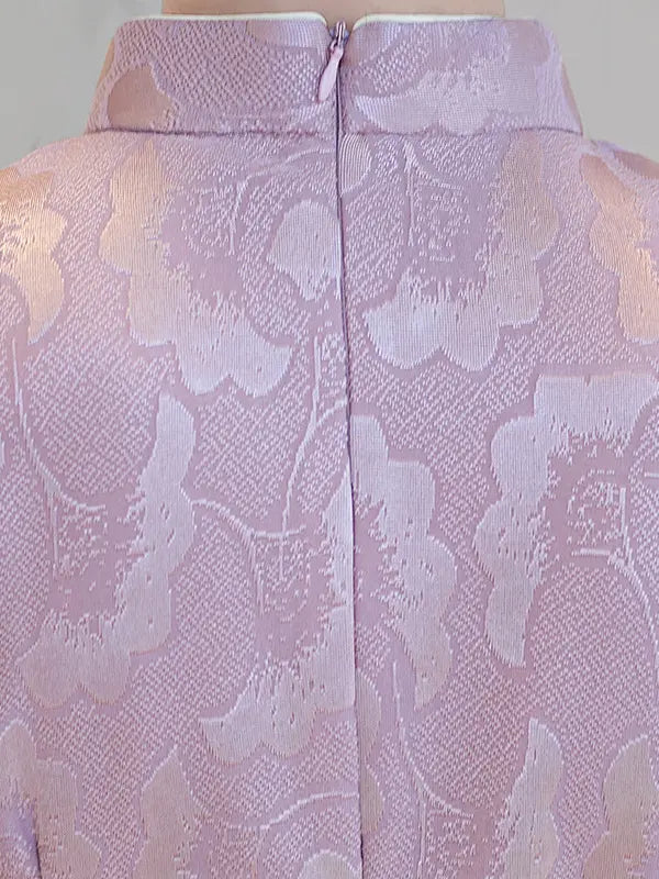 Close-up of the back of a lavender and light pink brocade jacket with a high mandarin collar and a central zipper.