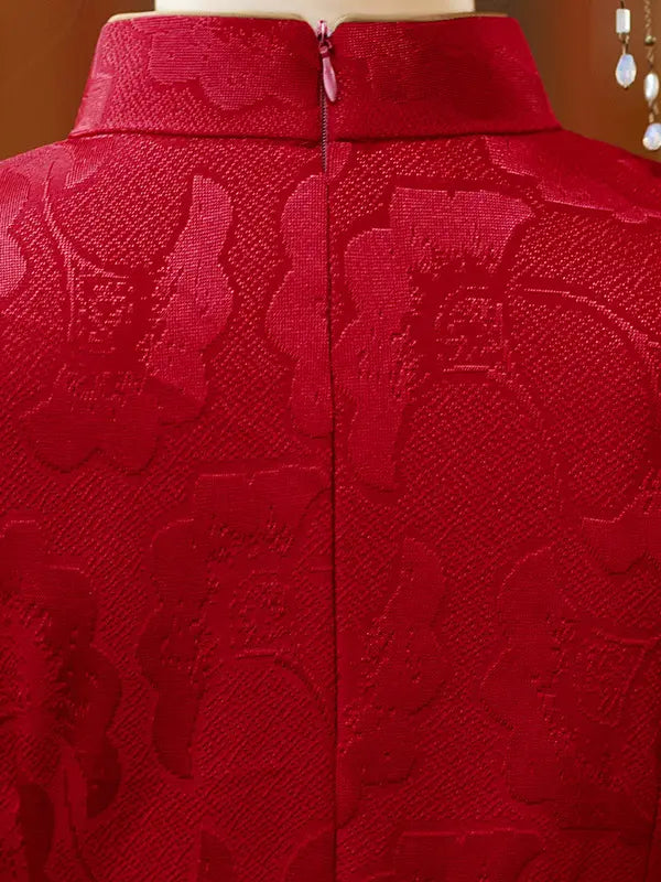 Close-up of the back of a red textured jacket or coat with a high collar and a central zipper, shown on a mannequin against a warm brown background.