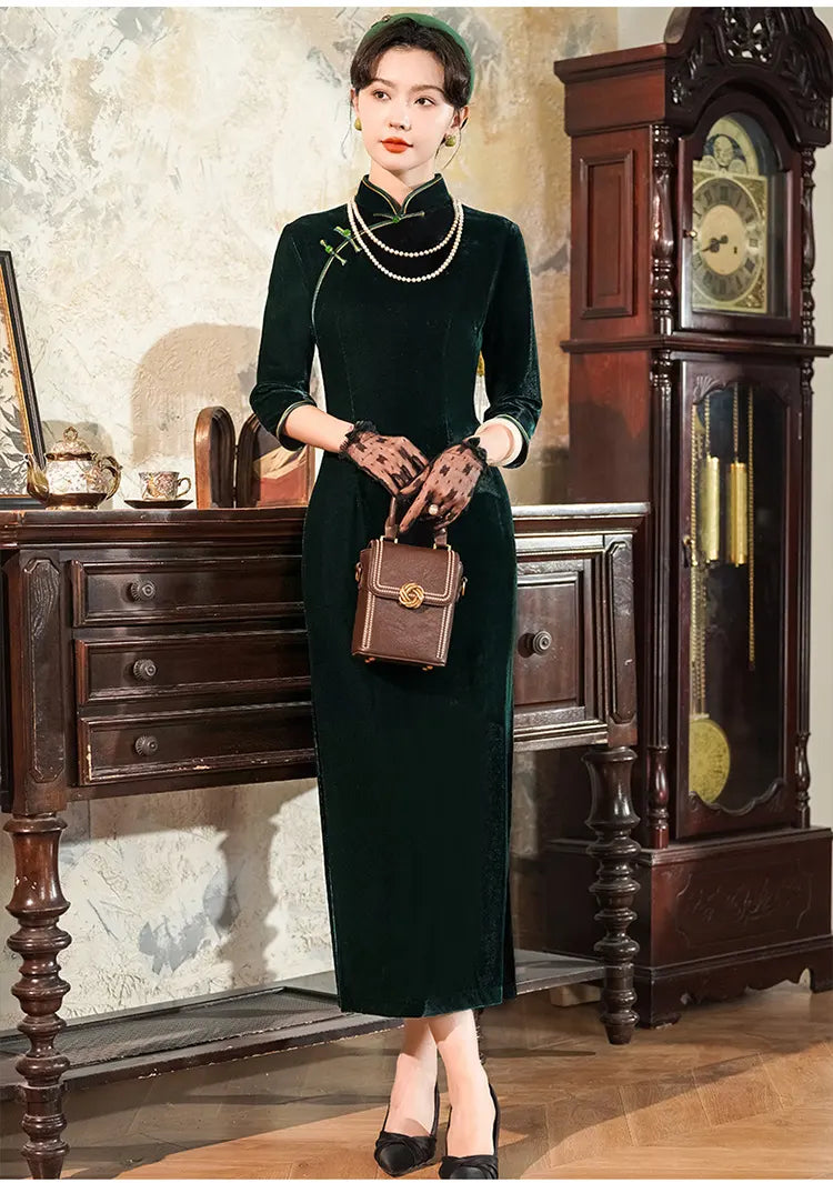 Woman in a Vintage Emerald Green Velvet Long Sleeves Qipao Dress  holding a brown handbag in an elegant room with wooden furniture.