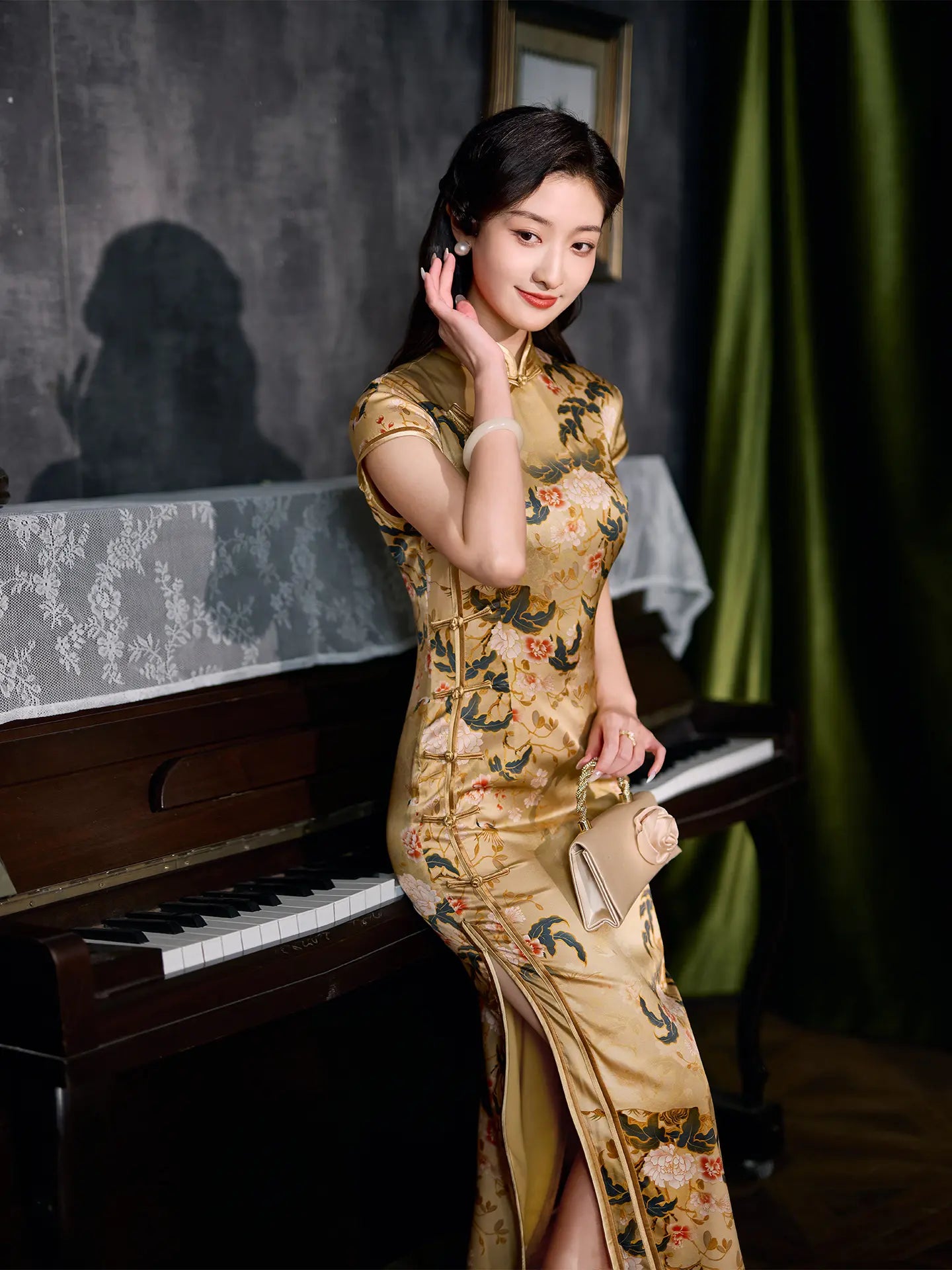 Woman in a Vintage Gold Peony Silk Long Qipao Dress dress standing next to a piano in a dimly lit room.