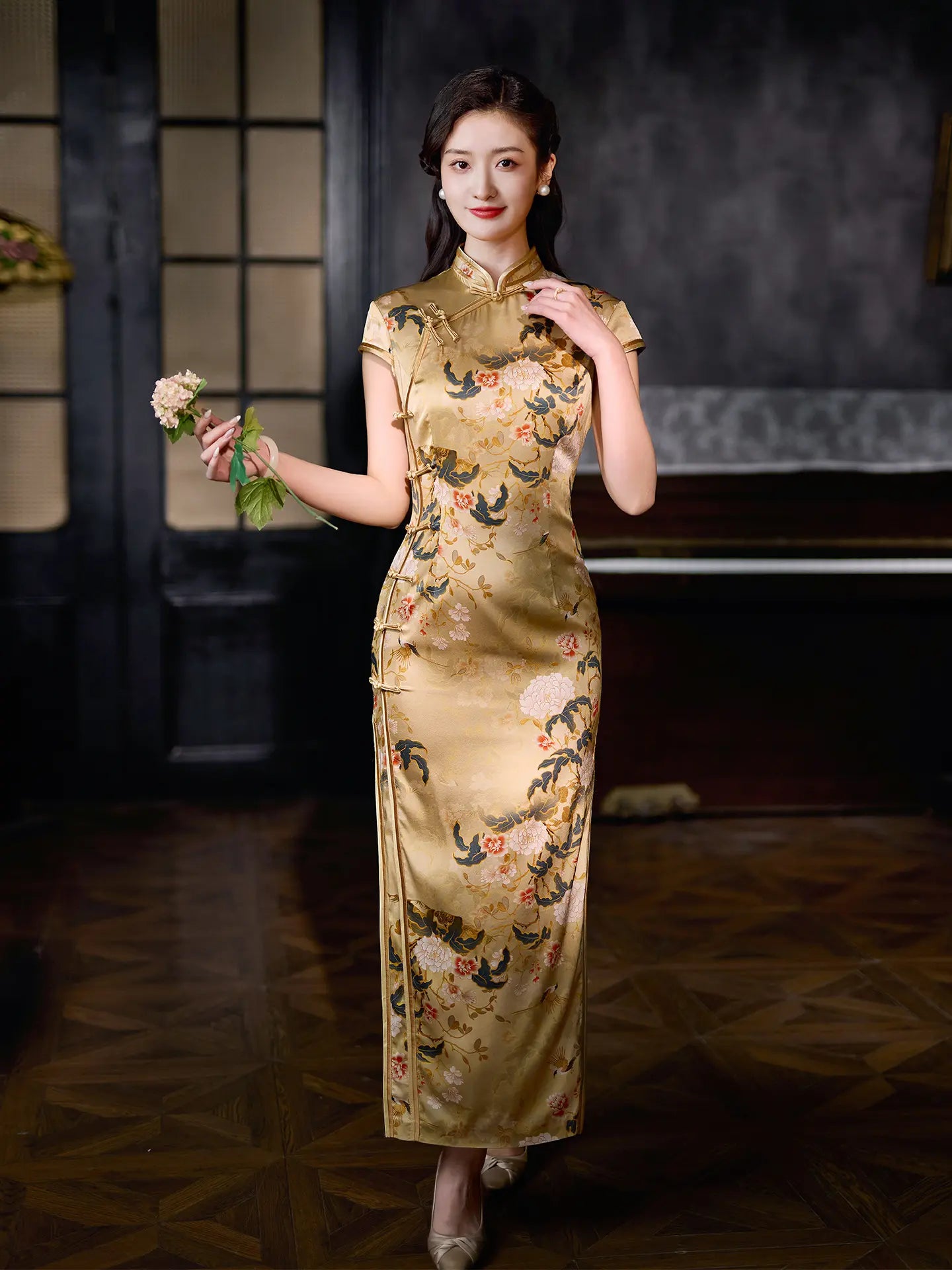 Woman in a traditional Chinese Vintage Gold Peony Silk Long Qipao   dress with floral patterns in a dimly lit room.